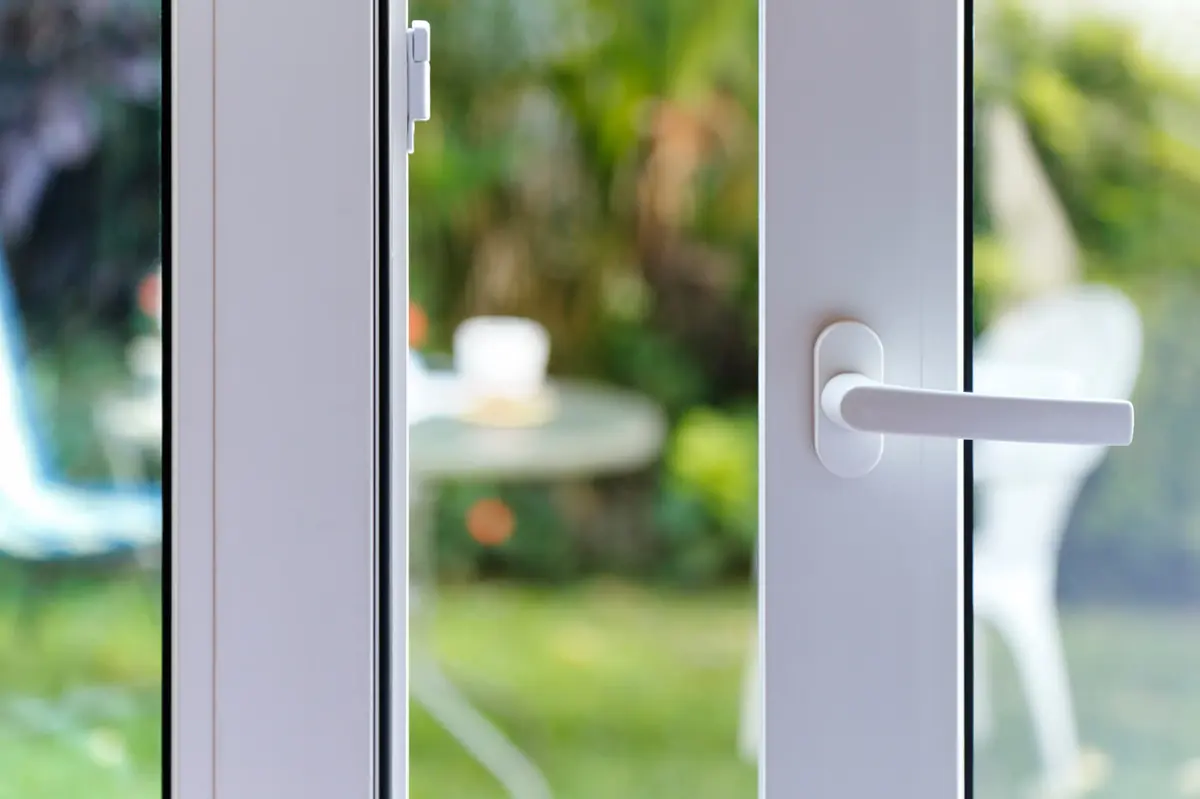 Close-up of a clean white sliding glass door handle and stile on a freshly serviced patio door